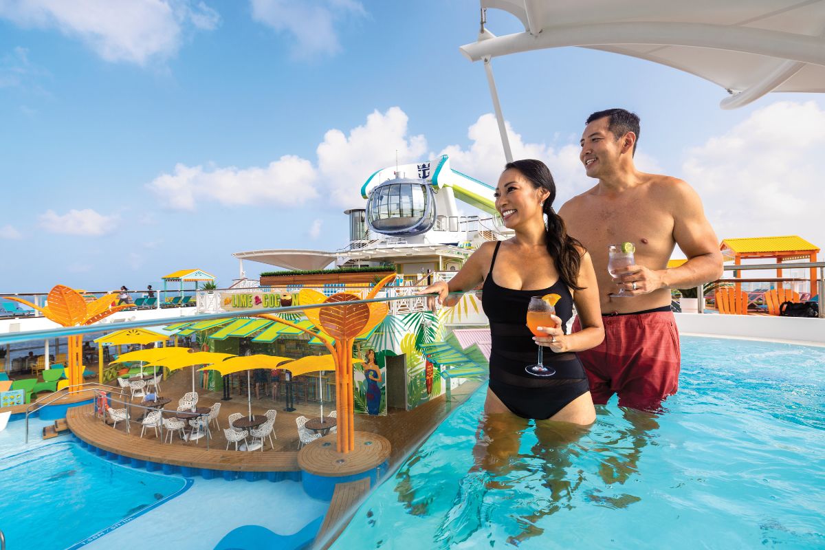 Happy couple enjoying a tropical cocktail in the pool on board a cruise ship