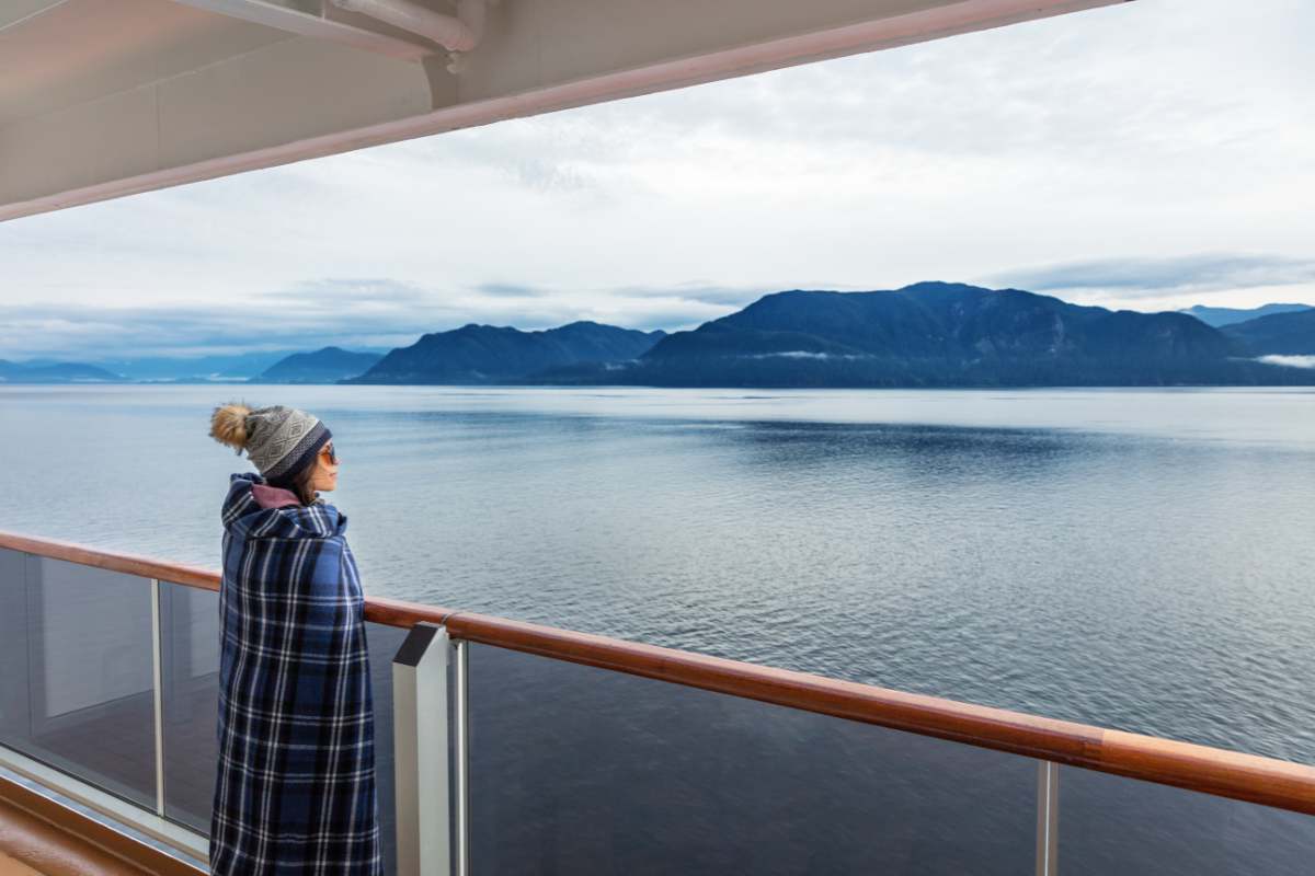 Woman enjoying breathtaking views of Alaska coast on board a cruise ship